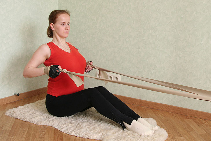 ► Упражнение «Тяга жгута к животу сидя на полу» для тренировки мышц спины в домашних условиях